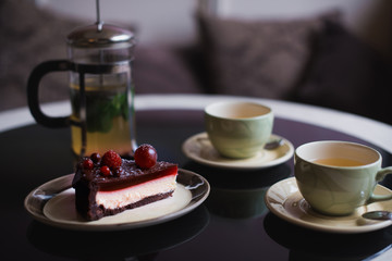 Piece of chocolate cake with cup of tee and fresh berry on black background
