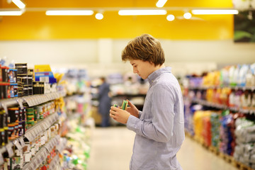 Man shopping in supermarket reading product information. Checking list.