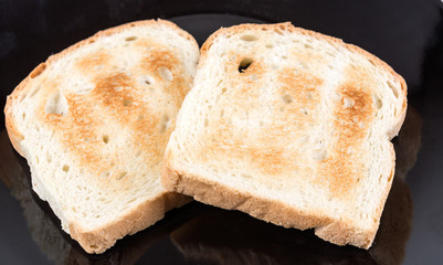 Two whole grain slices of bread toasted on a ceramic plate isolated on white background