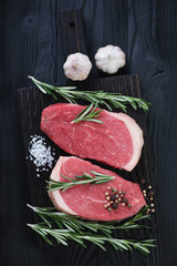 Raw fresh beef medallion steaks over black wooden background