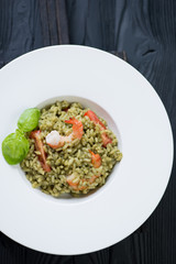 White plate with spinach risotto, overhead view, studio shot