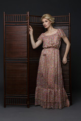 Beautiful girl standing near folding screen 