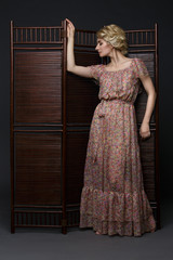 Beautiful girl standing near folding screen 