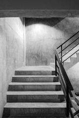 Empty modern rough concrete stairway with black steel handrail