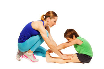 Fototapeta na wymiar Female trainer teaching kid boy stretching legs