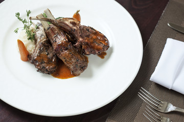 Plate with roast ribs  of lamb with potato  on color back