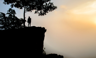 The silhouette picture of a woman standing on the top of the mountain