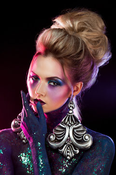 Young attractive blonde girl in bright art-makeup, in purple tones. Rhinestones and glitter body painting.