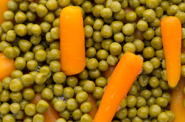 Carrots with green peas vegetable background.