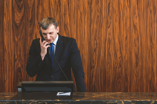 Male receptionist talking on phone with guest