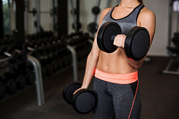 Fototapeta na wymiar Woman doing exercises with dumbbells in the gym
