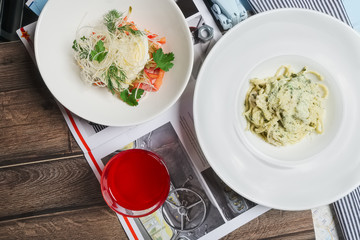 Glass of fruit-drink, spaghetti with cheese and cheese and veget