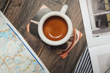 Cup of espresso near map and magazine on the table. Top point of