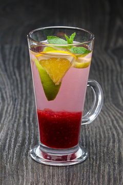 Tall transparent glass with raspberry and citrus tea.