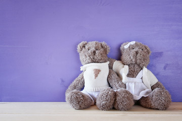 cute teddy bears couple hugging on wooden table