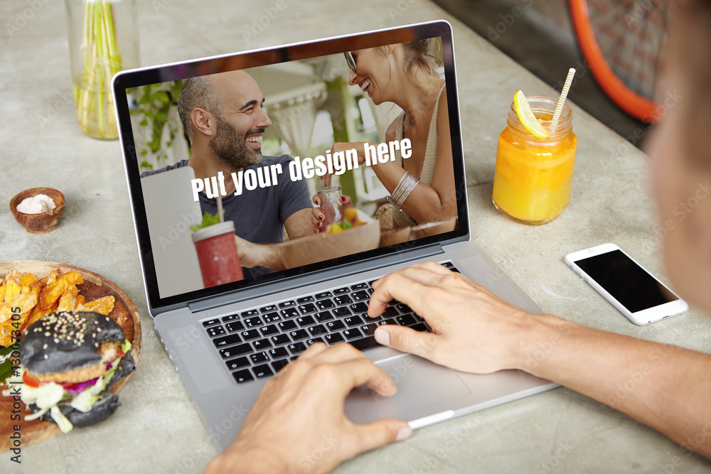 Poster young self-employed man working on his project on generic laptop while sitting at cafe and using fre