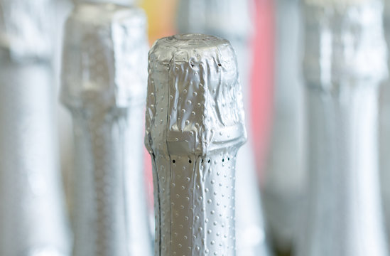 Silver champagne bottle necks and top caps at standing the light background in liquor store.