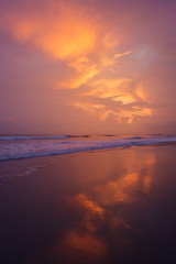 Naklejka premium Sunset clouds and waves on empty beach