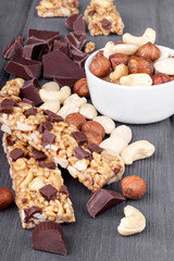 Obraz na płótnie Canvas Variety of nuts, granola bars and chocolate on wooden background