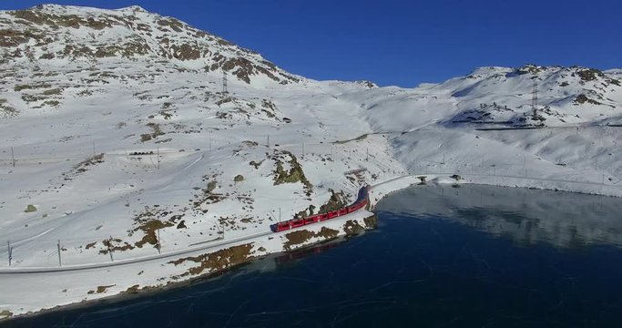 Aerial 4k - Bernina Express - Passo del Bernina - Vista aerea del trenino rosso e del lago Bianco ghiacciato con pattinatori