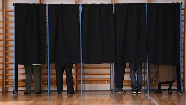 Unrecognizable people casting votes into the ballot box during elections