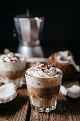 Coconut latte on a wooden table. Broken coconut. Low key food photo.
