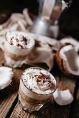 Coconut latte on a wooden table. Broken coconut. Low key food photo.