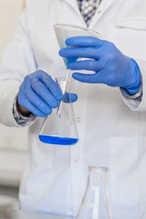 Fototapeta premium Laboratory technician performs tests and pouring blue liquid