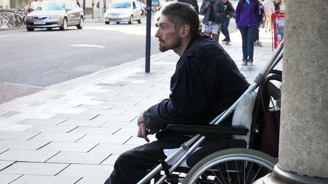 homeless bagging in the street: young disable on wheel chair 
