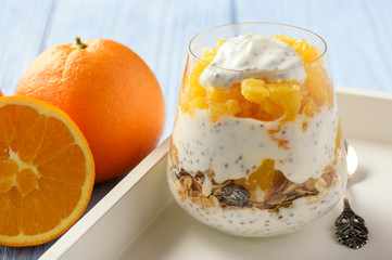Yogurt dessert with muesli, chia seeds and oranges.