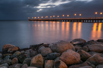 Seascape of stony shore and illuminated pier in Gdynia Or?owo at night. Poland.