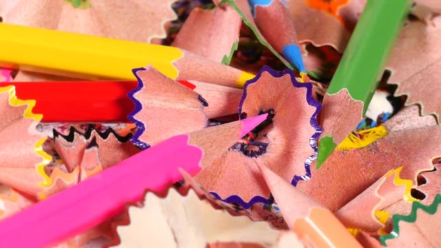 Few pencils of various colors with sharp ends lie on heap of pencil remains, creativity through drawing, art. Close up, seamless loop, rotation, 4K Ultra HD.