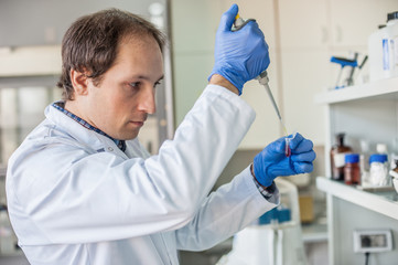 Scientist in the laboratory filling test tubes with pipette