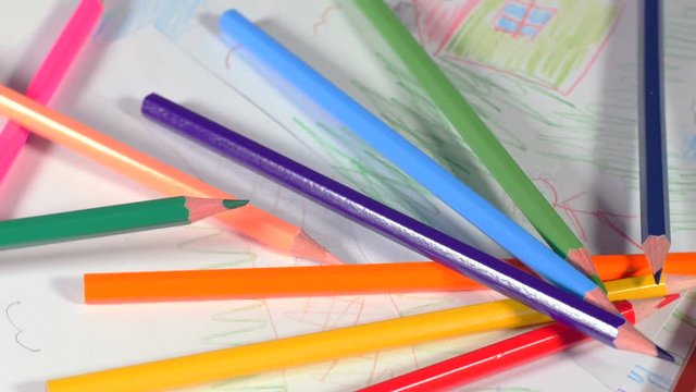 Wooden pencils scattered on table with kids pictures, drawing myself and house, art in school, developing creativity. Closeup, rotation, 4K Ultra HD.