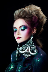 Young attractive blonde girl in bright art-makeup, high hair, body painting. Rhinestones and glitter