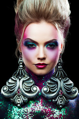 Young attractive blonde girl in bright art-makeup, high hair, body painting. Rhinestones and glitter