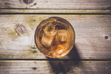 Overhead shot of glass of whiskey on wooden table