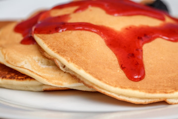 Delicious pancakes with red sweet strawberry syrup