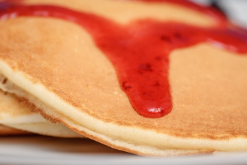 Delicious pancakes with red sweet strawberry syrup