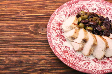 Chicken breasts braised with olives on plate on woden table