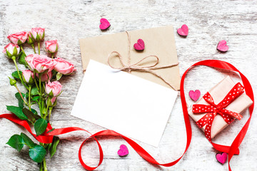 blank white greeting card with pink roses, wooden hearts and gift box