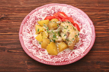 oven baked chicken fillet with potatoes and rosemary on woden table