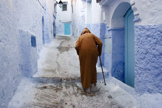 Old man walking in a typical street in Chefchaouen, Rif mountains region, Morocco