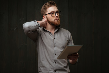 Portrait of a thoughtful bearded man using tablet computer