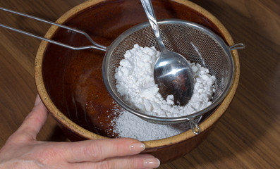 Puderzucker wird für Weihnachtsgebäck durch ein Sieb gerieben