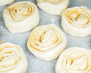 Obraz na płótnie Canvas Closeup of raw cinnamon roll and cinnamon buns on baking paper