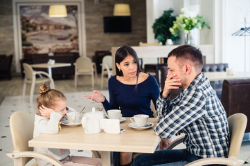 Couple fighting in front of child at cafe or restaurant.
