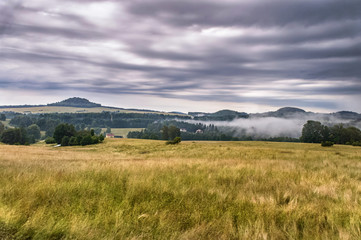 Obraz premium Expanse of green fields with hilly forests