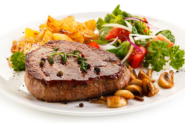 Grilled steak, baked potatoes and vegetable salad on white background 