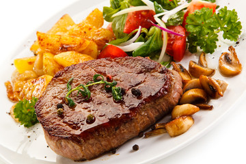 Grilled steak, baked potatoes and vegetable salad on white background 